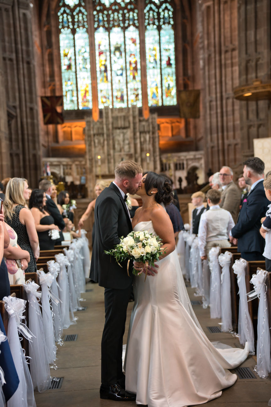 A bride and groom kiss in the isle at St George's Church London Road, Stockport