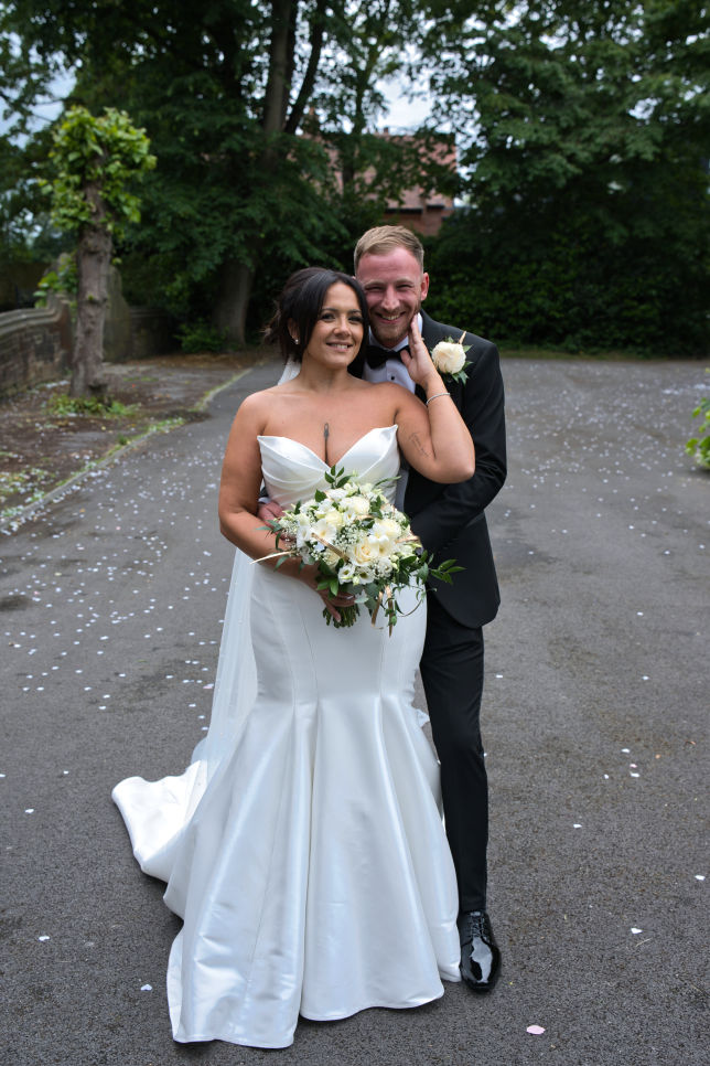 A bride and groom have a loving embrace on the grounds of St George's Church London Road, Stockport
